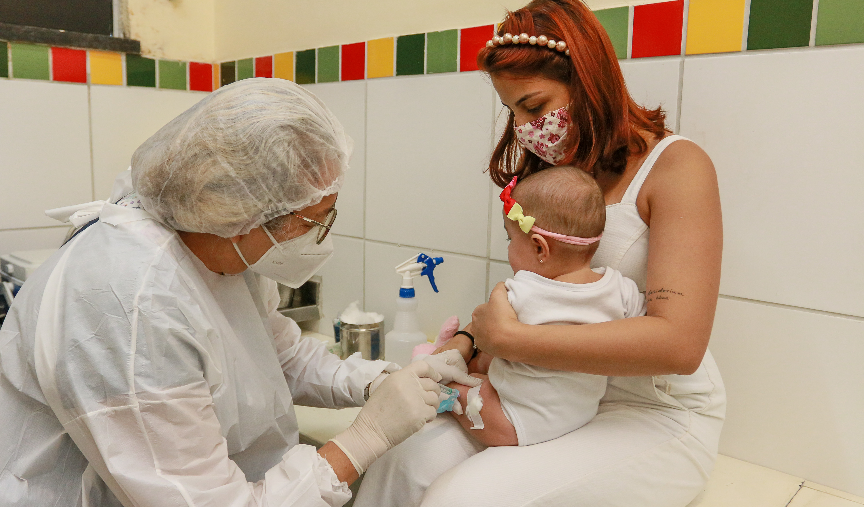 enfermeira vacina uma bebê que está no colo da mãe